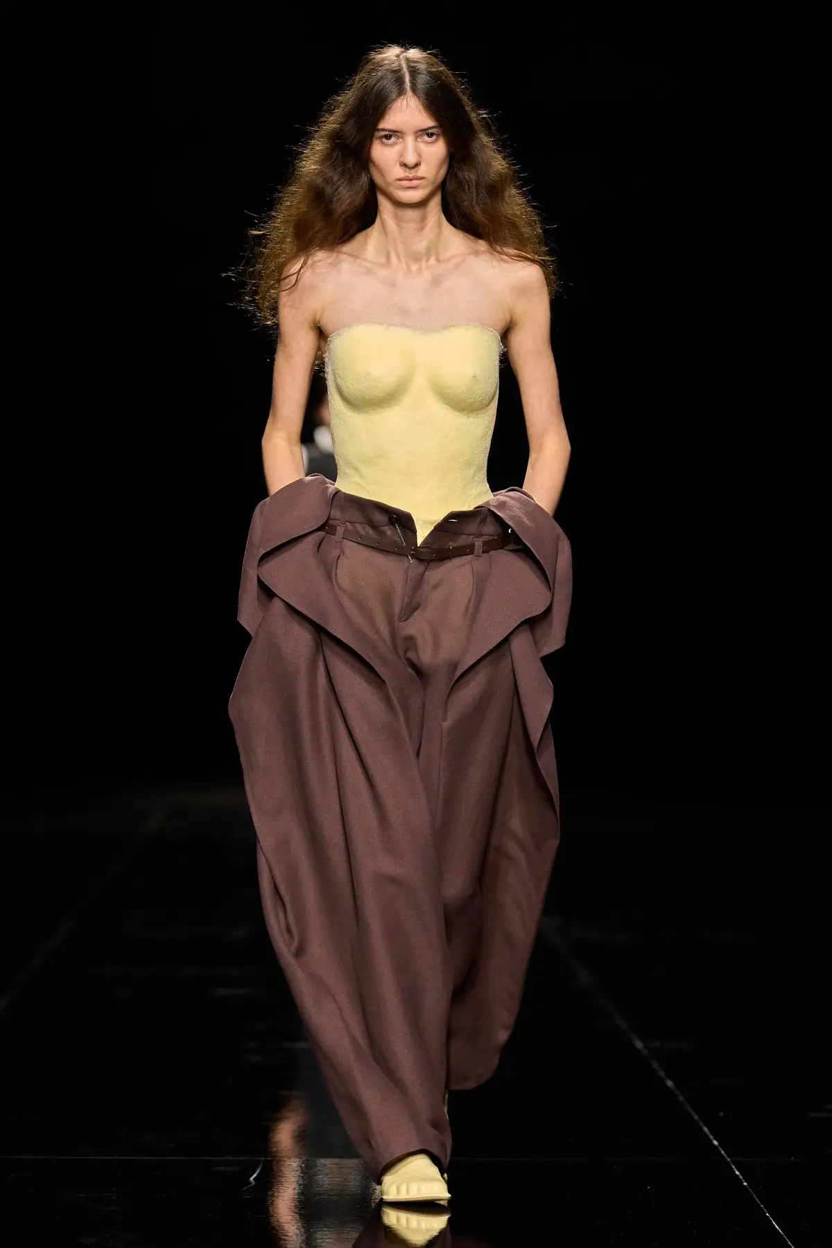 Issey Miyake SS27, Look 2. A moulded bodice over full brown trousers.