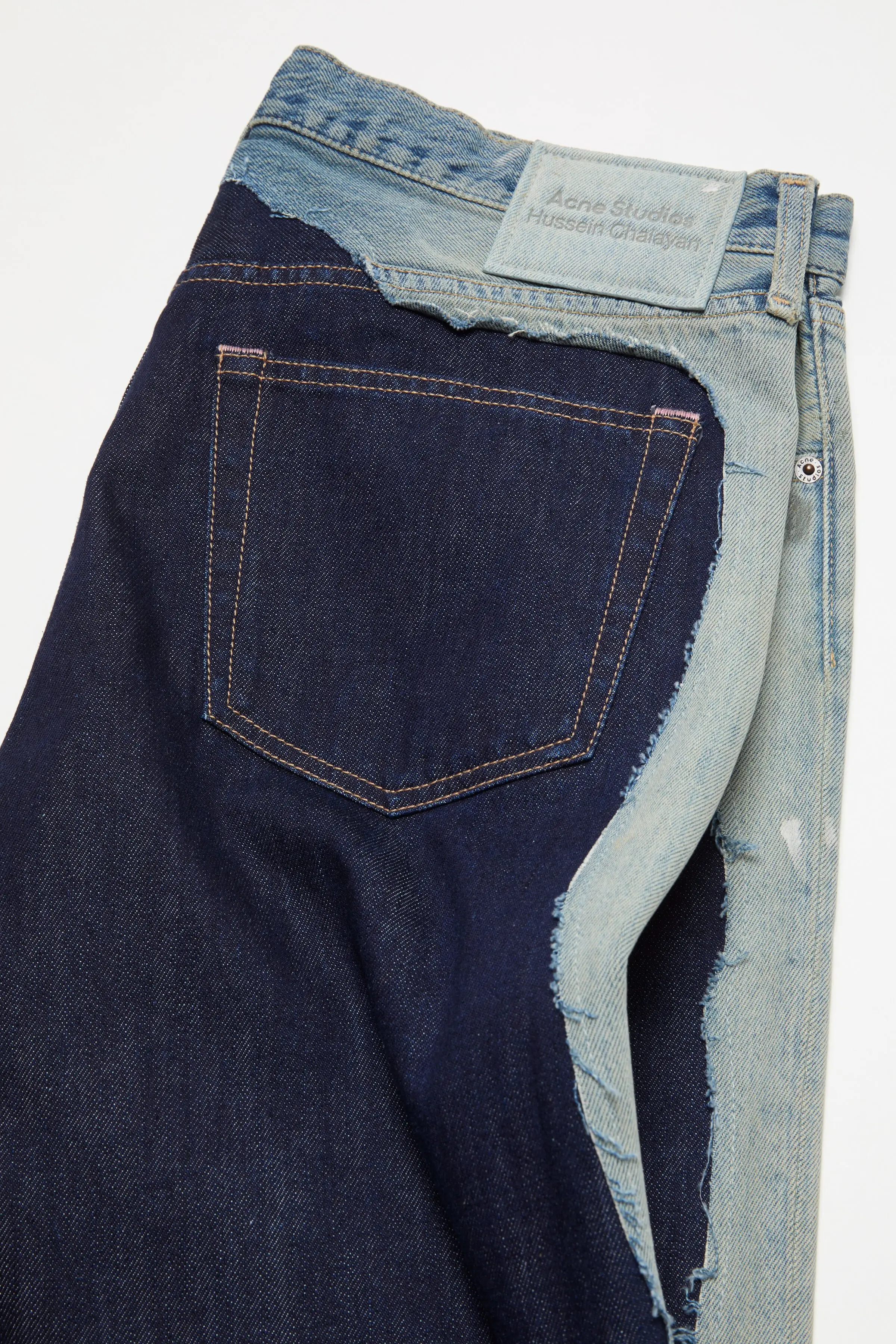 The back pocket. Frayed faded denim around a clean dark patch.