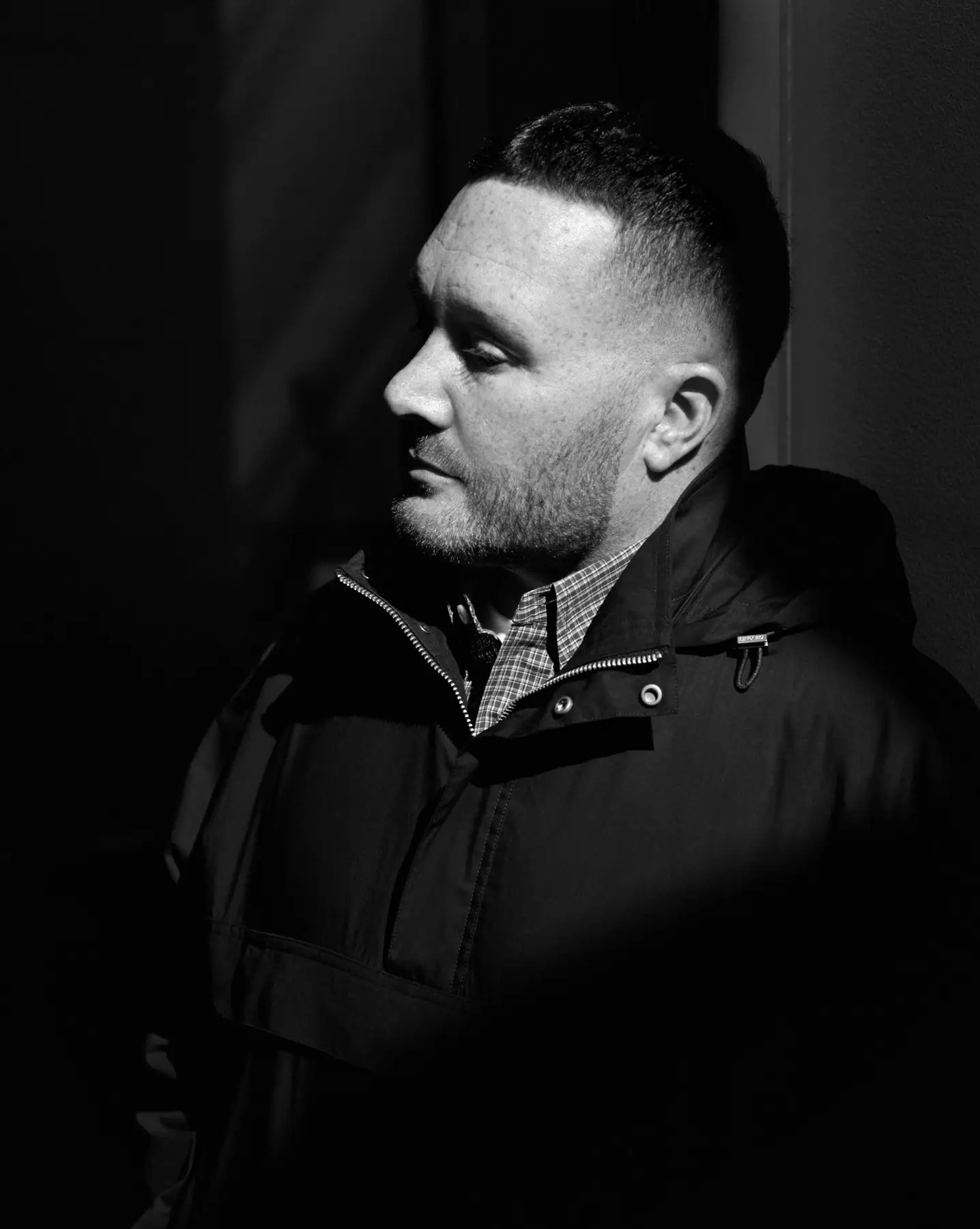 Kim Jones in profile, in black, against a dark background.