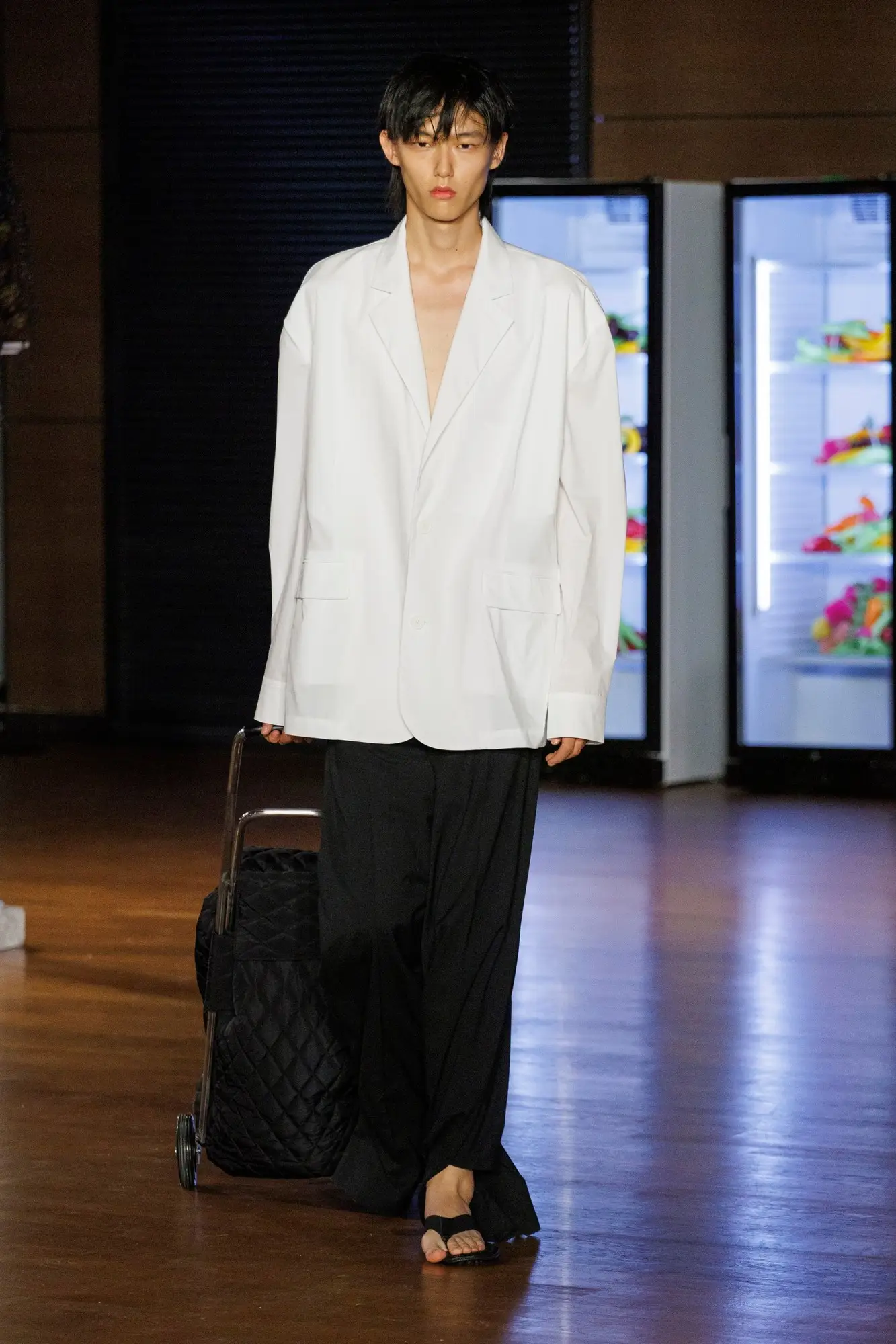 Look 7. White shirt, black trousers, a black quilted trolley.