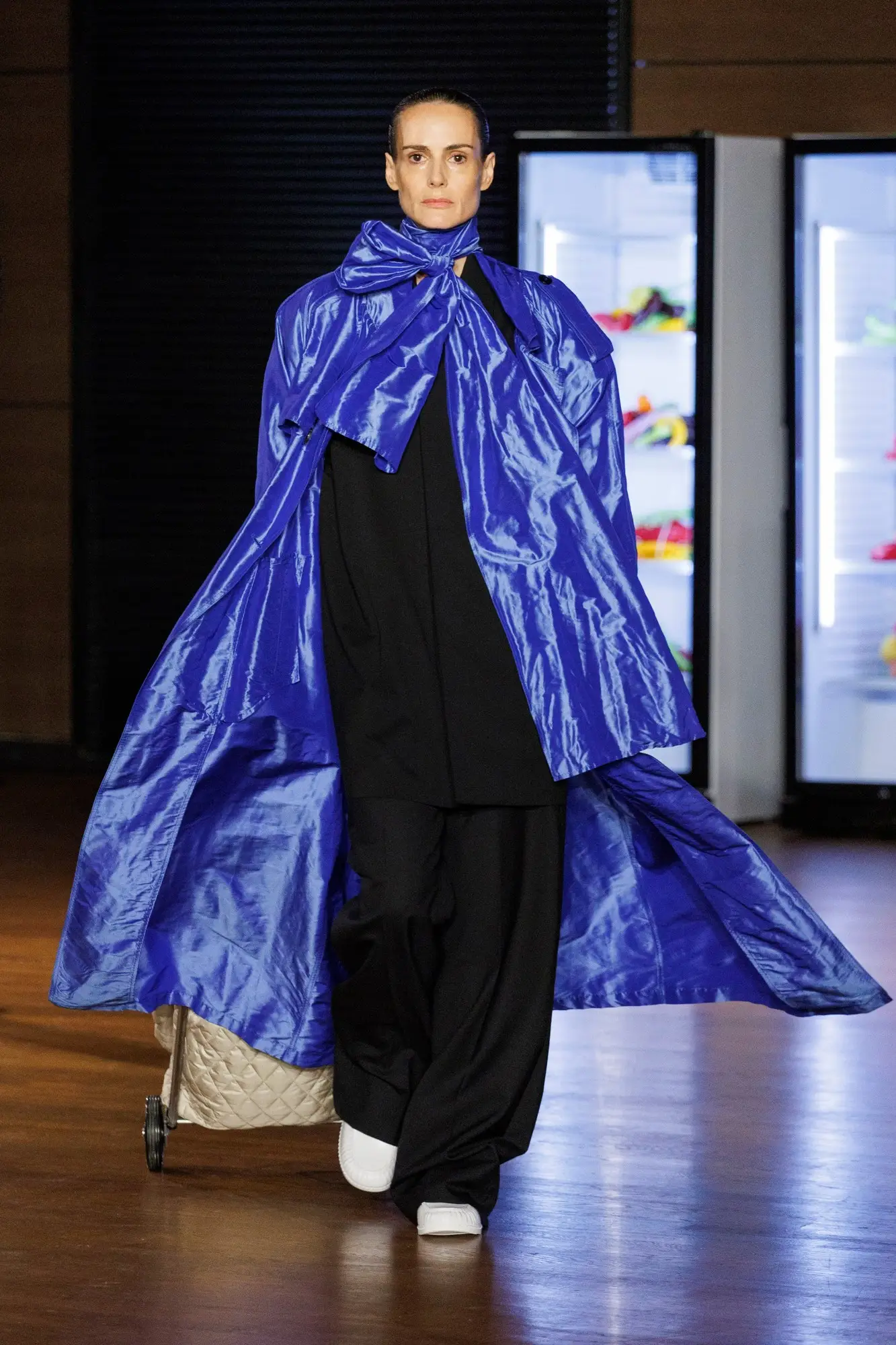 Look 45. Blue cape, a cream quilted trolley at the hem.