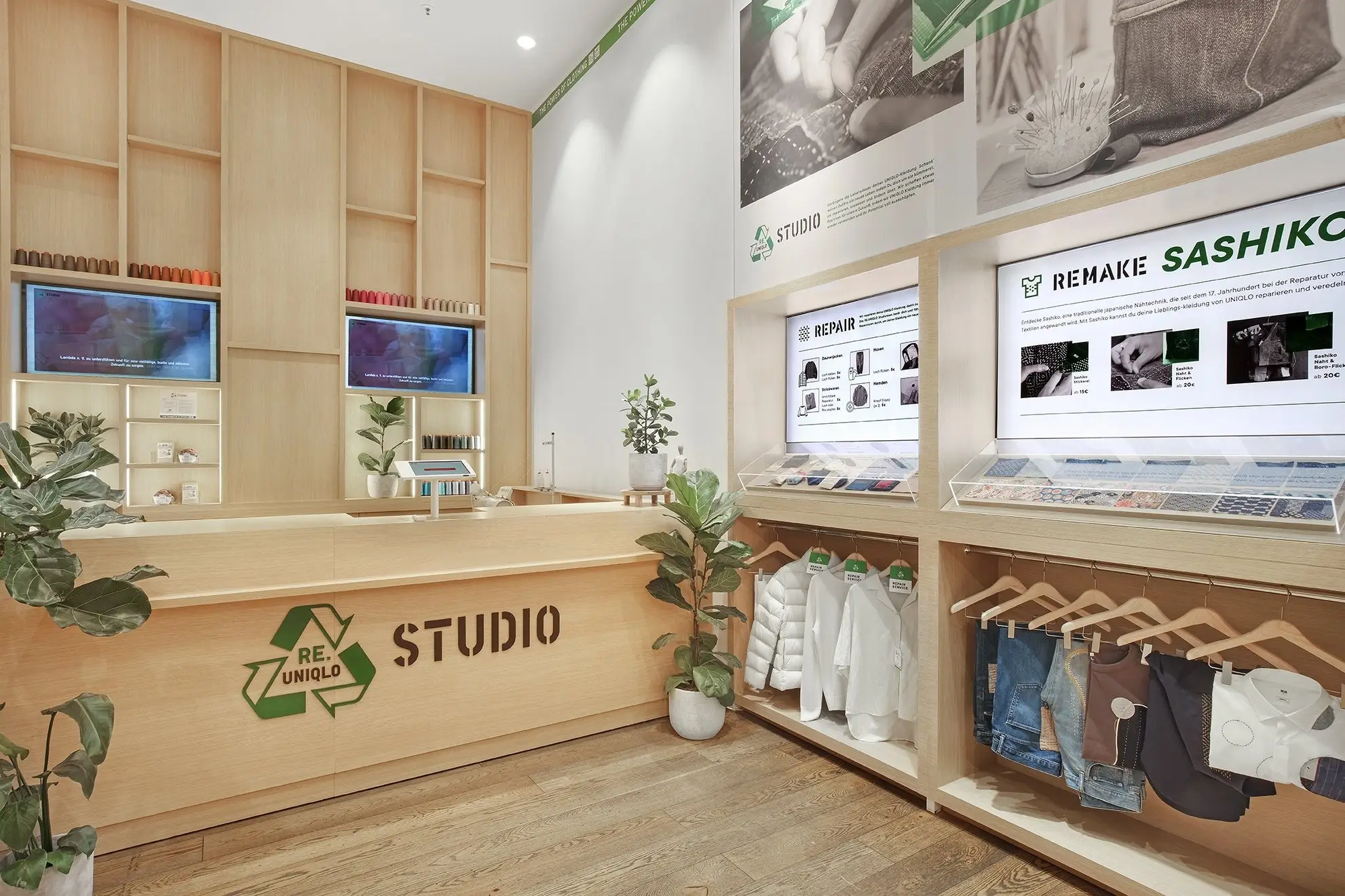 The RE.UNIQLO STUDIO counter in Uniqlo Tauentzien, Berlin: a wooden desk, screens marked Repair and Remake Sashiko, and repaired clothes on hangers.
