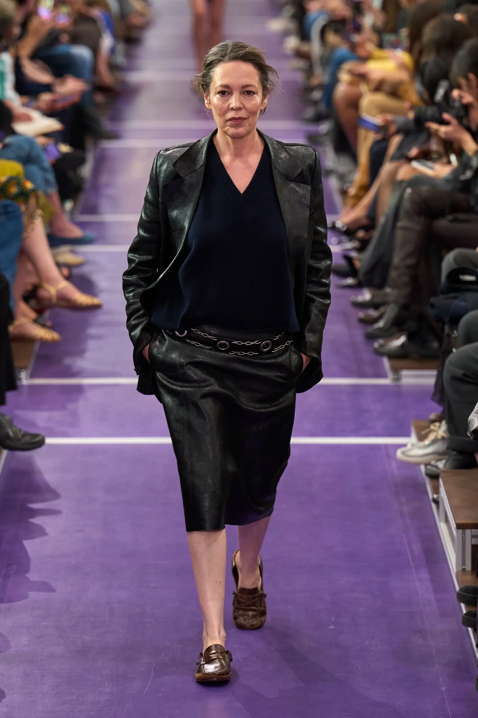 Miu Miu SS27, Look 24. Olivia Colman in a black leather jacket and skirt.